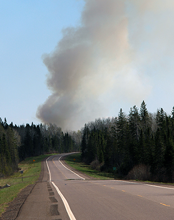 A plume of smoke rises over a prescribed burn in the woods near Highway 2 in Lake County.